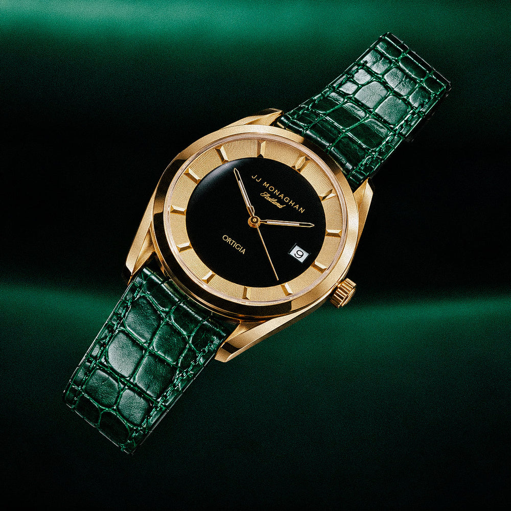 The Ortigia watch on a green leather strap against a green background